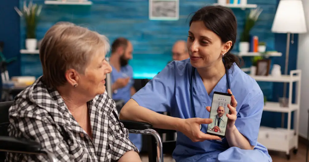 Patient and doctor are having a telehealth visit via smartphone with a nurse holding the phone