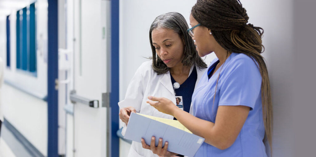 Nurse holding a document while talking to a doctor.