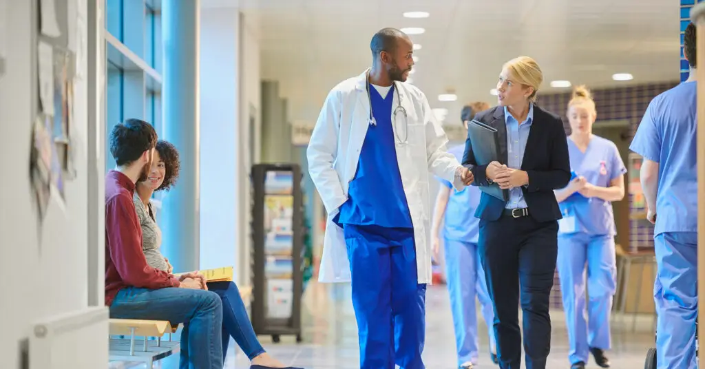 Medical director speaking with an executive as they walk down a hospital hall