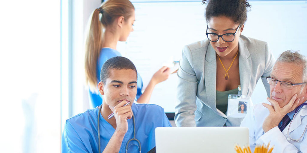 Doctor, nurse, and health professional looking at a laptop.