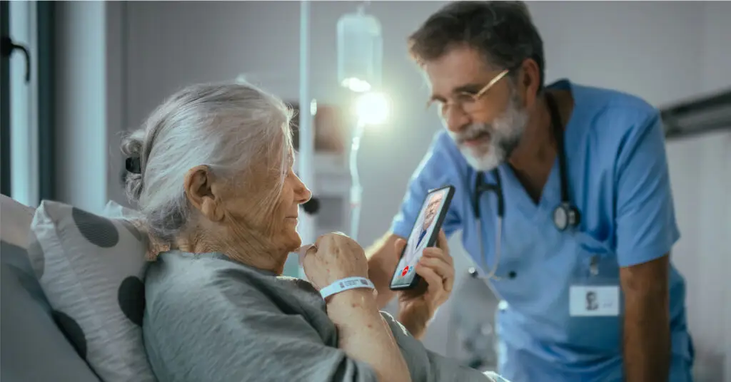 Patient speaking with a doctor via smartphone during a telemedicine visit, a nurse is in the background