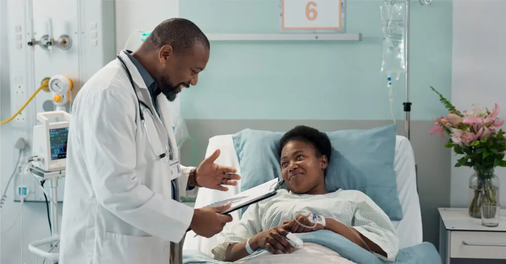 doctor focused on the patient experience at the patient's hospital bedside happily discussing medical information