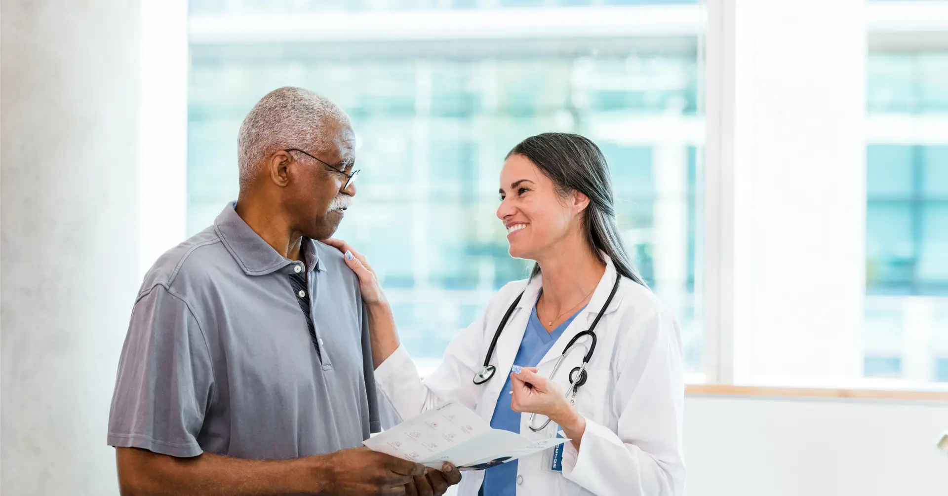 doctor smiling at patient while patient holds medical pamphlet in his hands